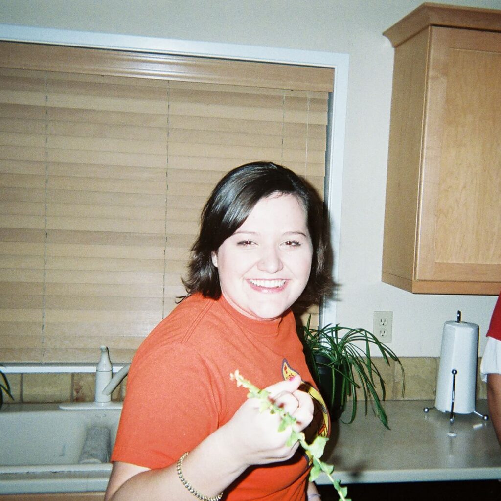 Me in college at a house party, smiling at the camera in a bright orange shirt.