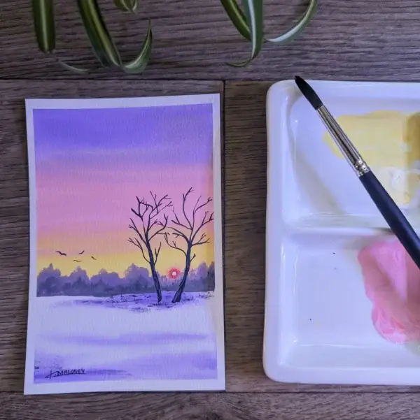 A watercolor painting of a purple, pink, and yellow sky, with a fiery red sun going down. The foreground is a purple snow field with two trees.