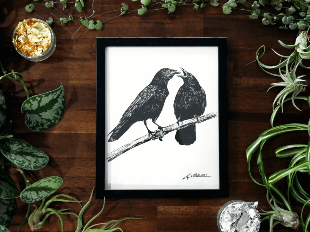 A framed print of the crow family. The Crow Family art print is a black and white image two crows. The one on the left is looking at the one on the right which has it's mouth open like it has something to say. The art print is surrounded by green plants, with some gold and silver leaf in two of the corners.