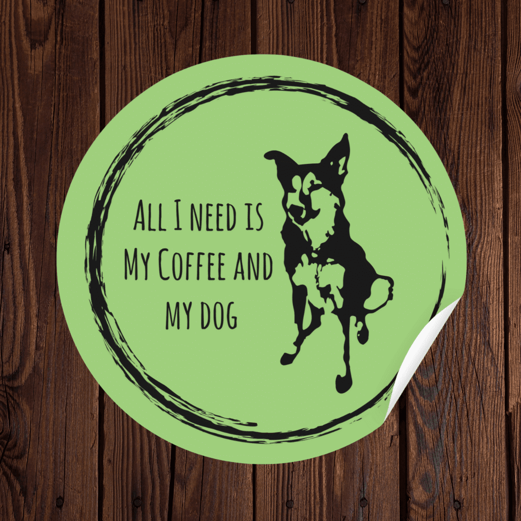 Green circular sticker on wood background reading 'All I Need Is My Coffee and My Dog' with black dog silhouette