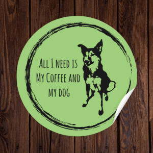 Green circular sticker on wood background reading 'All I Need Is My Coffee and My Dog' with black dog silhouette