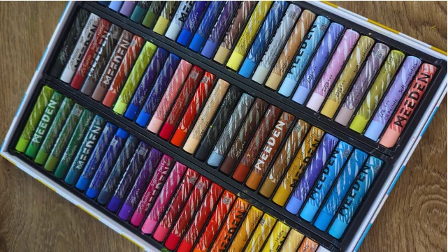 a set of colorful oil pastels laying on a worktable.